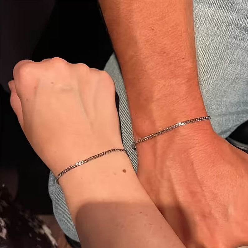 Close-up of two wrists wearing silver bracelets.